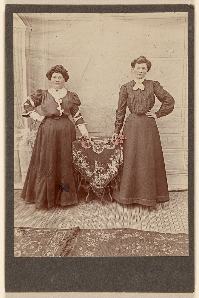 Two women standing at a table holding flowers