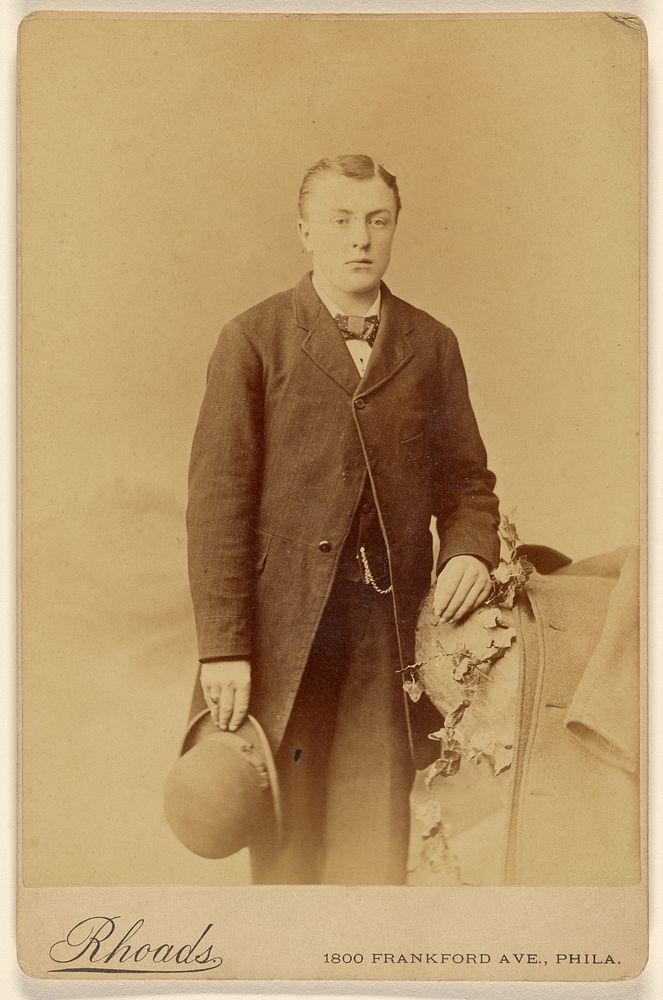Man holding derby, standing by William H Rhoades