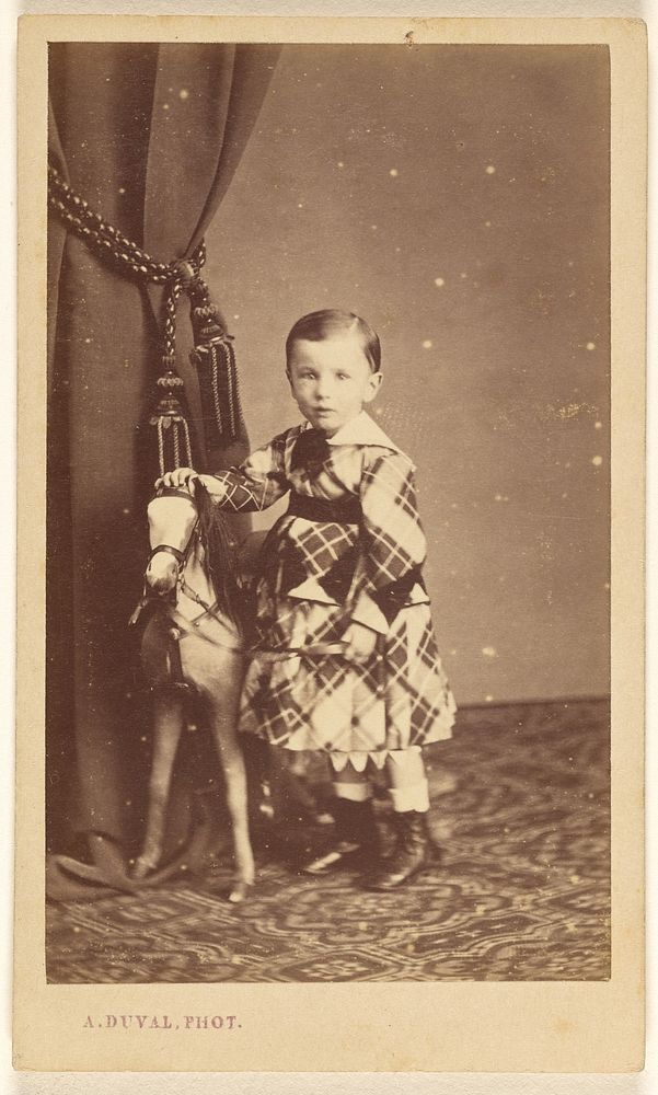 Unidentified little boy standing with toy pony by A Duval