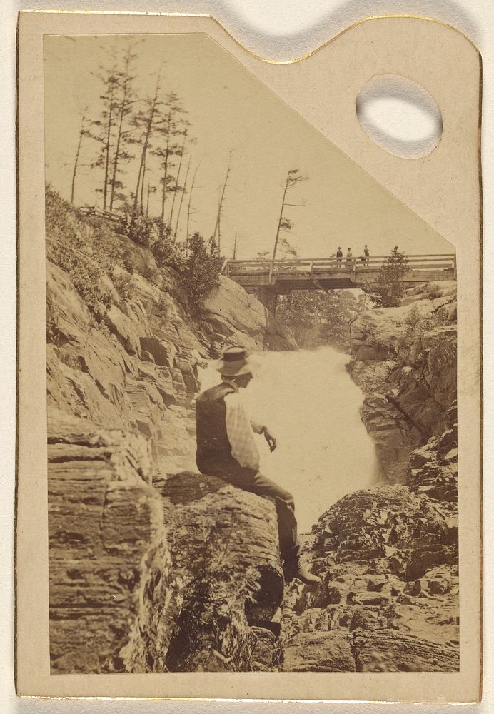 Unidentified man sitting on rocks near a waterfall