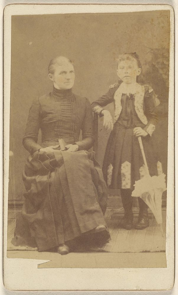 Mother sitting with a book in her lap, girl standing with an umbrella