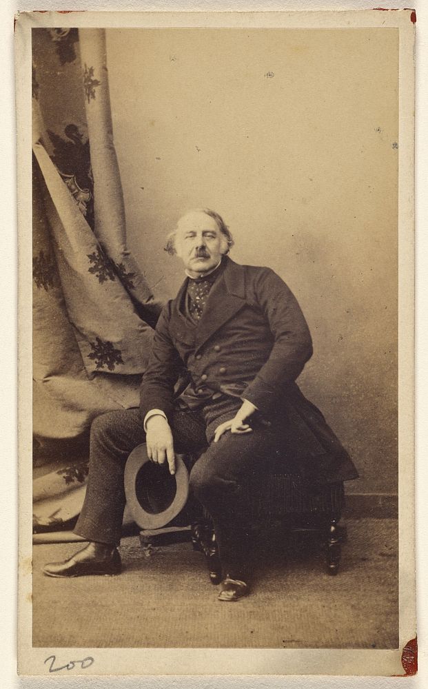 Unidentified man with longish hair and mustache, seated on hassock, holding hat by Gustave Le Gray