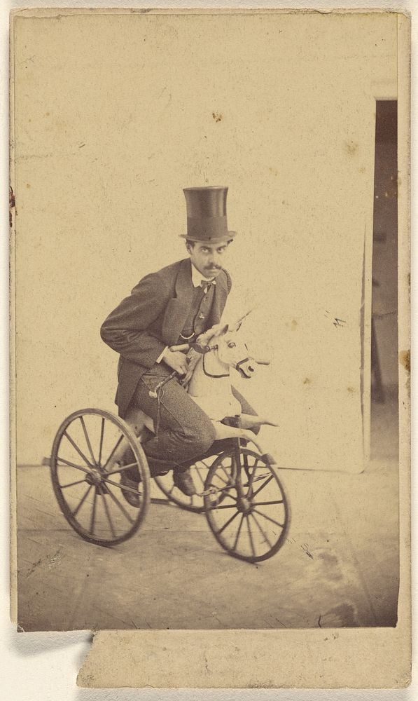 Man in a top hat riding a bicycle with a horse head