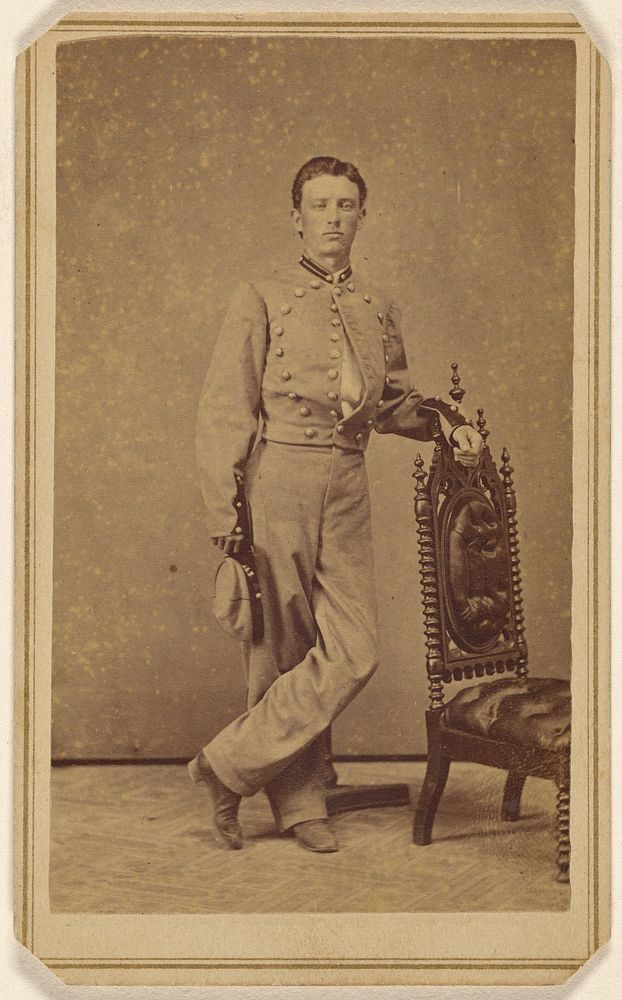 Portrait of a confederate soldier standing at ornate chair, holding cap by Young s Gallery