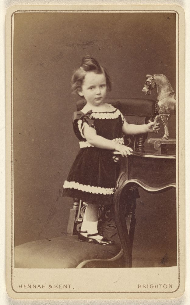 Gerard Carter. March 1875. Aged 20 months]/[Little child standing on a chair, holding a carved horse on a table by Hennah…
