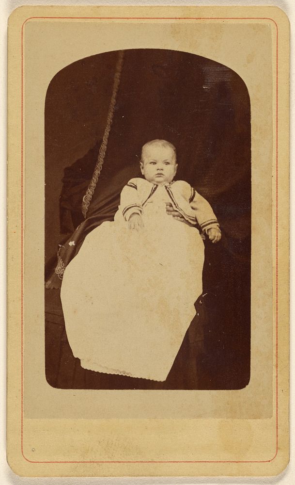 Baby in long gown, seated by E O Cook