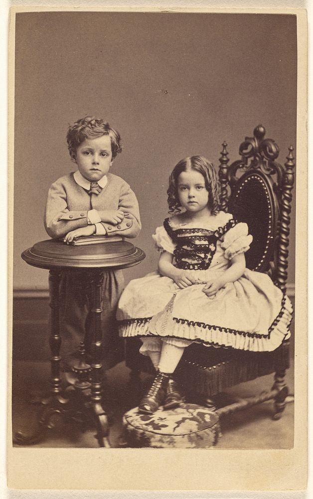 Two children: boy standing, leaning on a table; girl with curls, seated by Frederick Gutekunst