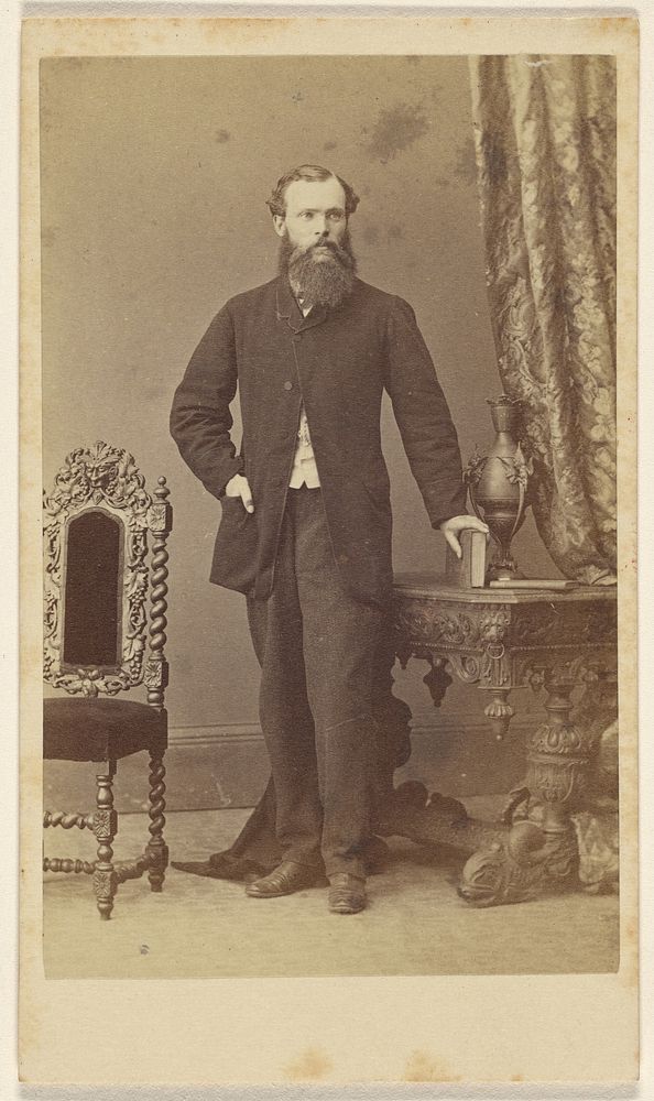 Full-bearded man, standing, with hand on book resting on table by Schwarzschild and Co