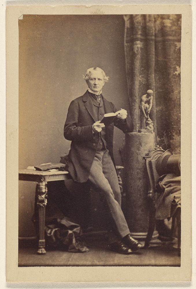 Unidentified man seated on table, holding an opened book by Camille Silvy