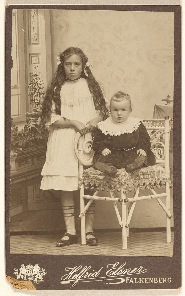 Unidentified girl with long hair, standing, and a baby girl, seated by Evie Helfrid Elsner