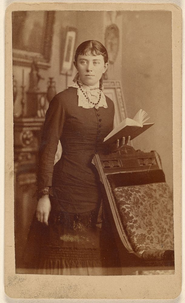 Unidentified young woman holding an open book, standing by Spury
