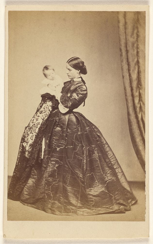 Unidentified woman holding a child, standing by A Crowe
