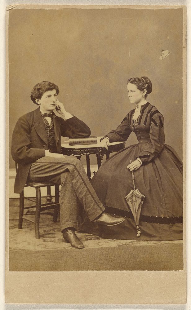 Unidentified couple seated: man with hand to cheek, elbow on book; woman holding a parasol by S G Sheaffer and Company