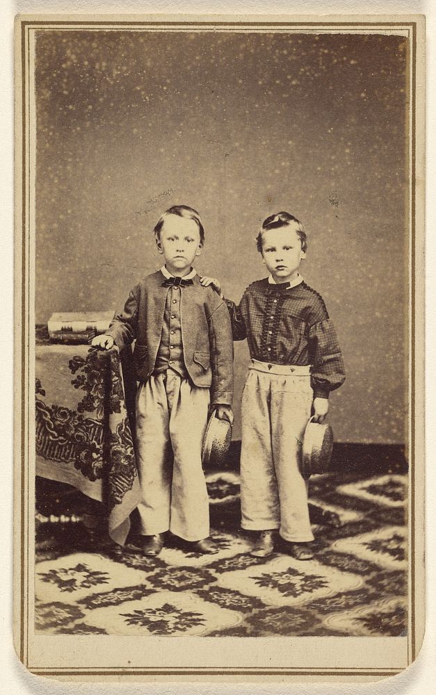 Two unidentified boys, each holding a hat, standing by J E Hoitt