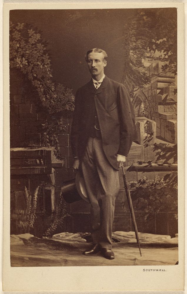 Unidentified man with moustache, holding a top hat and umbrella, standing by Southwell Brothers