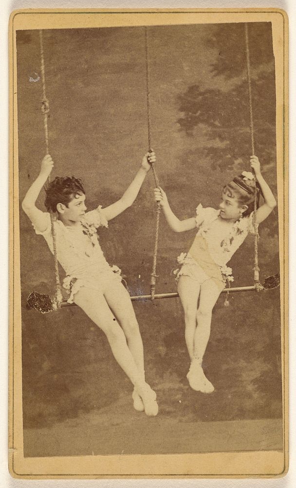 Two unidentified little girls in costumes on a swing by Casanas y Ca