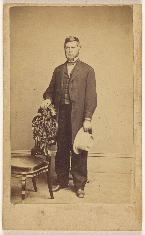 Unidentified man with long muttonchops, standing, holding a white hat by Charles E Crouse