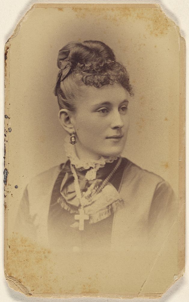 Unidentified woman with her hair in a bun, crucifix around her neck, printed in vignette-style by J B Scholl