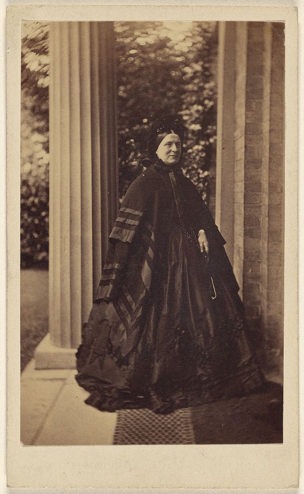 Unidentified elderly woman standing outside near column at house entrance by J G and E G Short