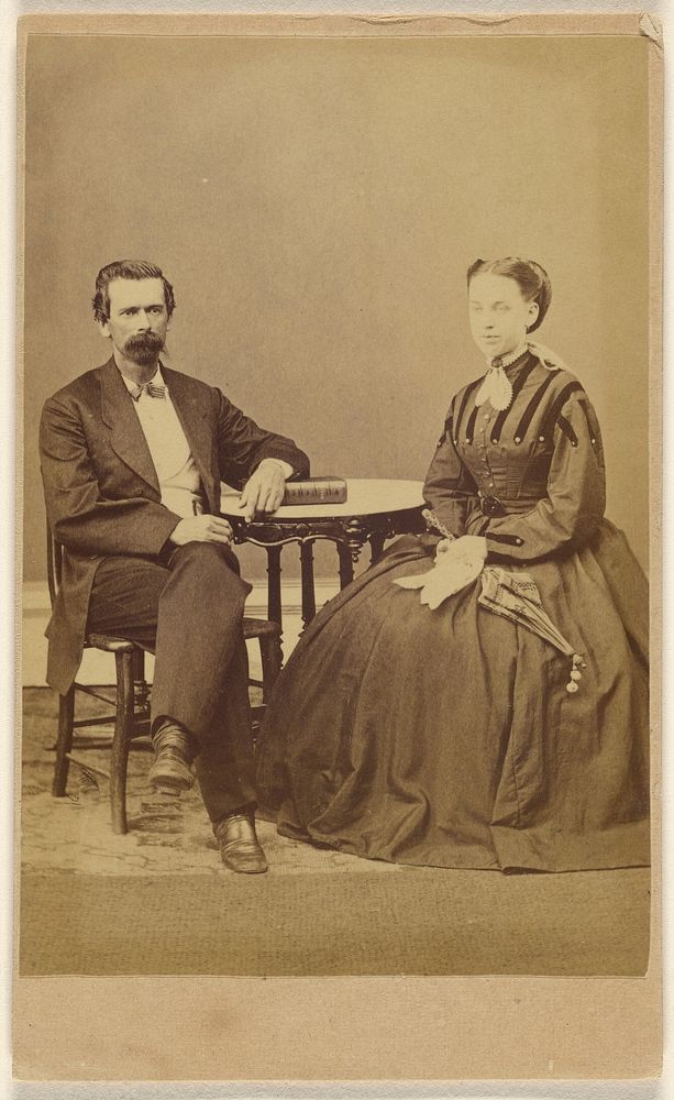 Unidentified couple, both seated at a table with a book on top; the man has a bushy moustache by S G Sheaffer and Company