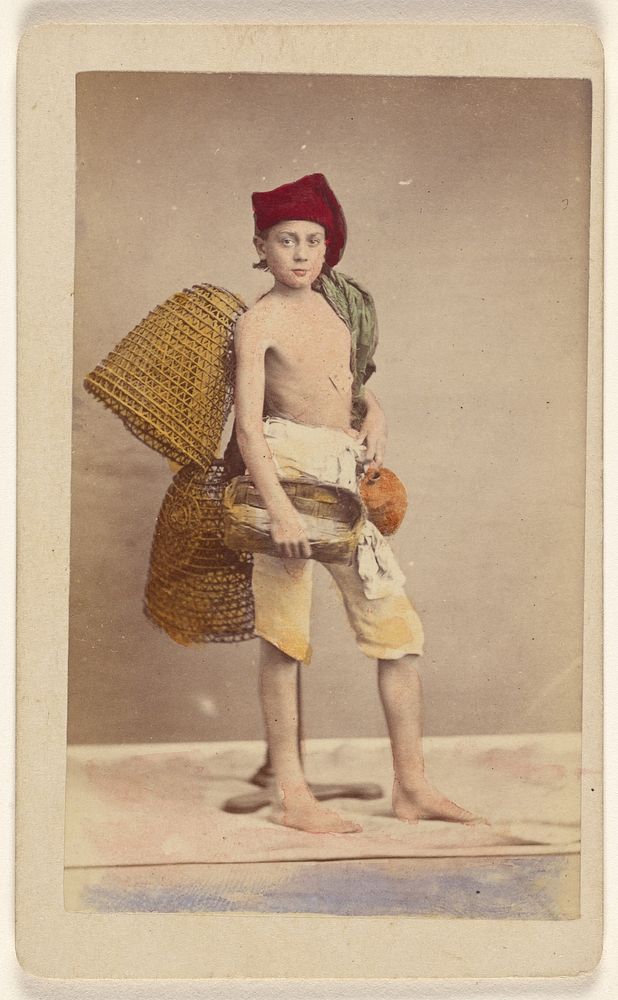 Unidentified boy wearing native costume with baskets on back and carrying a water jug and small basket, standing by Giorgio…