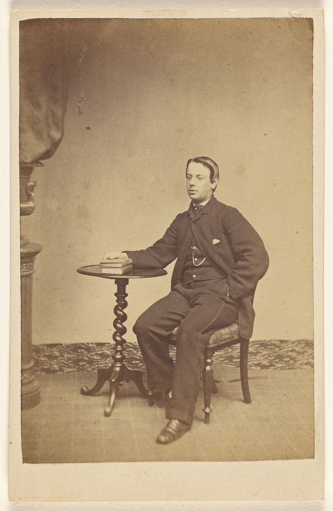 Unidentified young man seated at a table with one hand on books by A Crowe