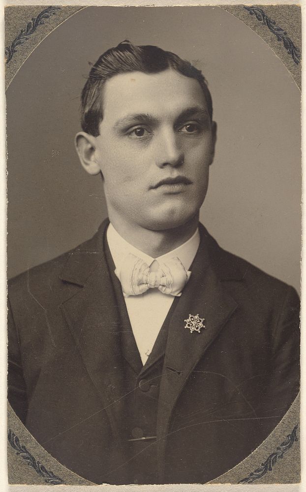 Unidentified young man wearing a white bow tie and a pin on his lapel