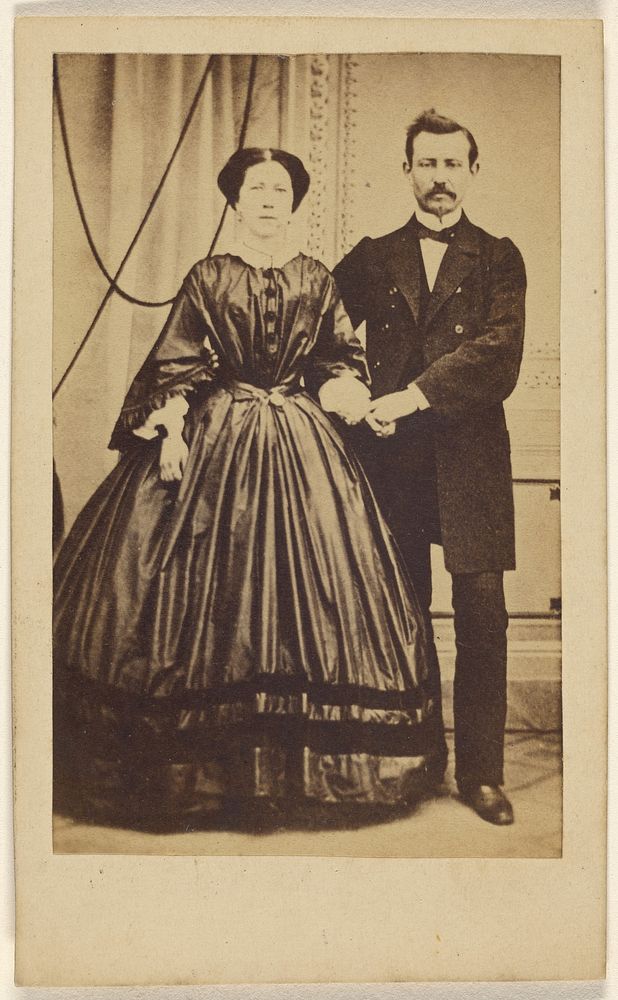 Unidentified couple: man with moustache and woman with her hair parted in the middle, both standing by Photographische…