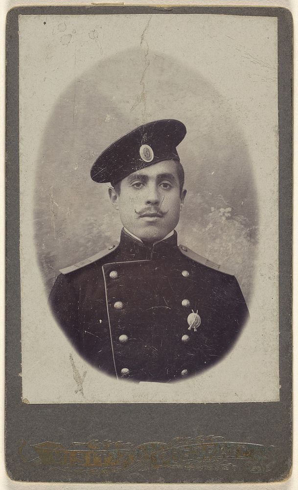Unidentified military man with moustache wearing a cap, a pin on his lapel