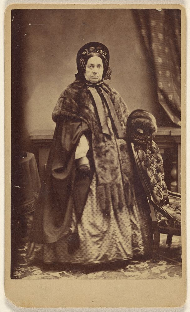 Unidentified elderly woman wearing a fur coat and hat, standing by Partridge