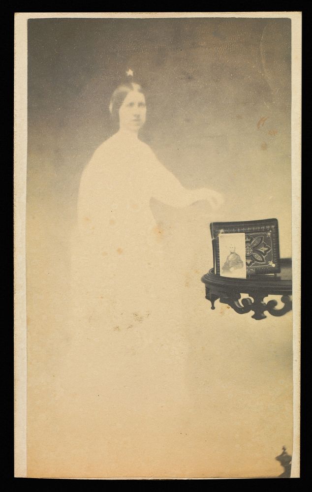 Female "spirit" with a carte-de-visite on a table propped against an album by William H Mumler and Helen F Stuart