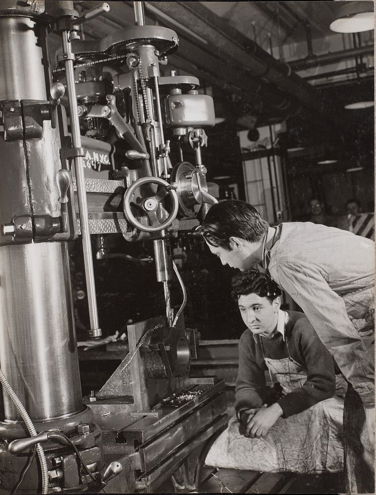 Two men sit near a large piece of machinery with a drill bit attached by Arnold Eagle