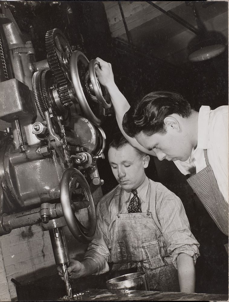 Two men look at machinery with a drill bit by Arnold Eagle