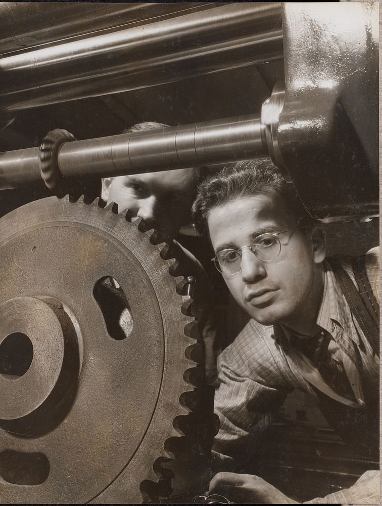 Close-up of a man working with a large gear by Arnold Eagle