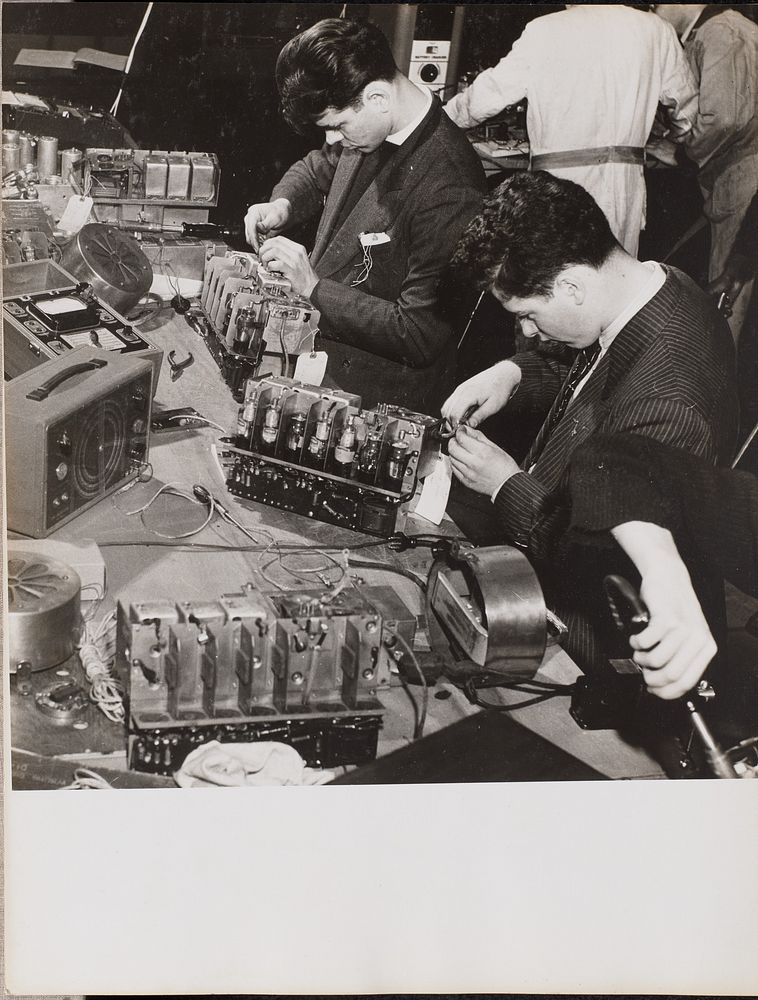 Two young men wearing blazers work on radios by Arnold Eagle