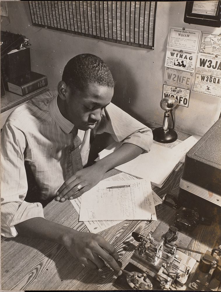 Young man sits at a desk reading hand-written notes by Arnold Eagle
