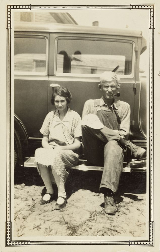 Man and woman sitting on running board of car by John William Piper