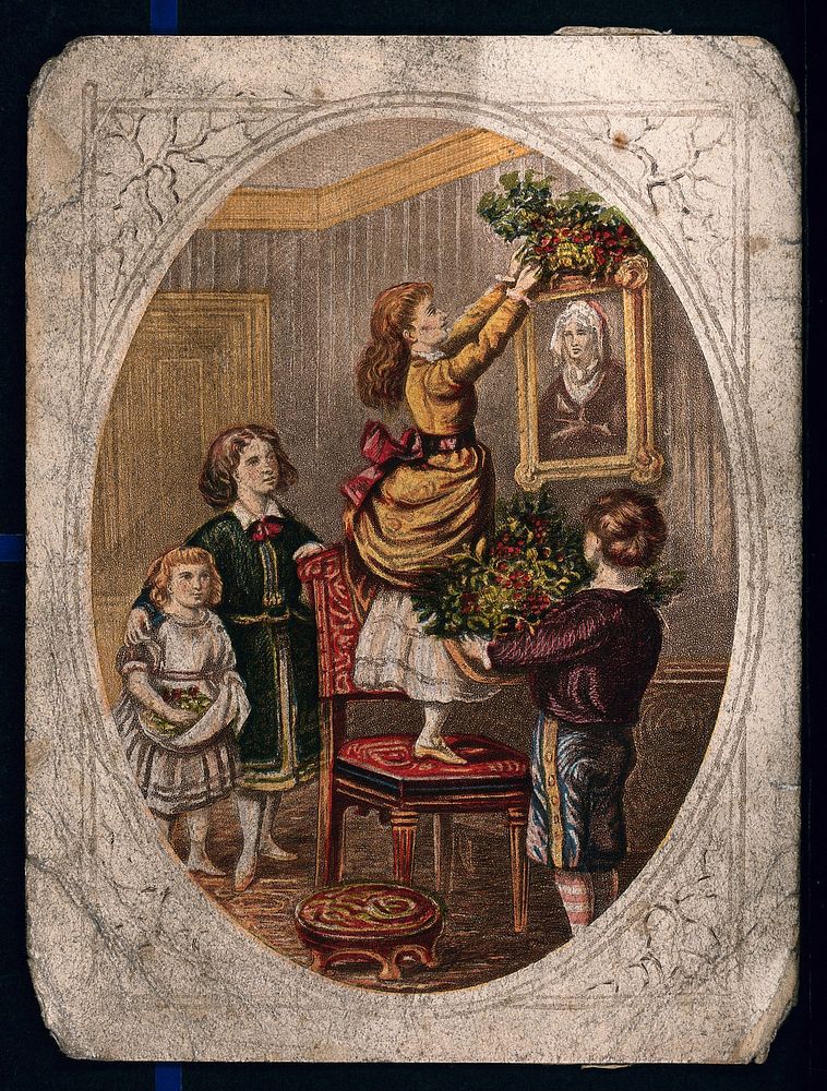 A child holds a large bunch of holly and two others watch as a young woman stands on a chair to reach the picture she is…