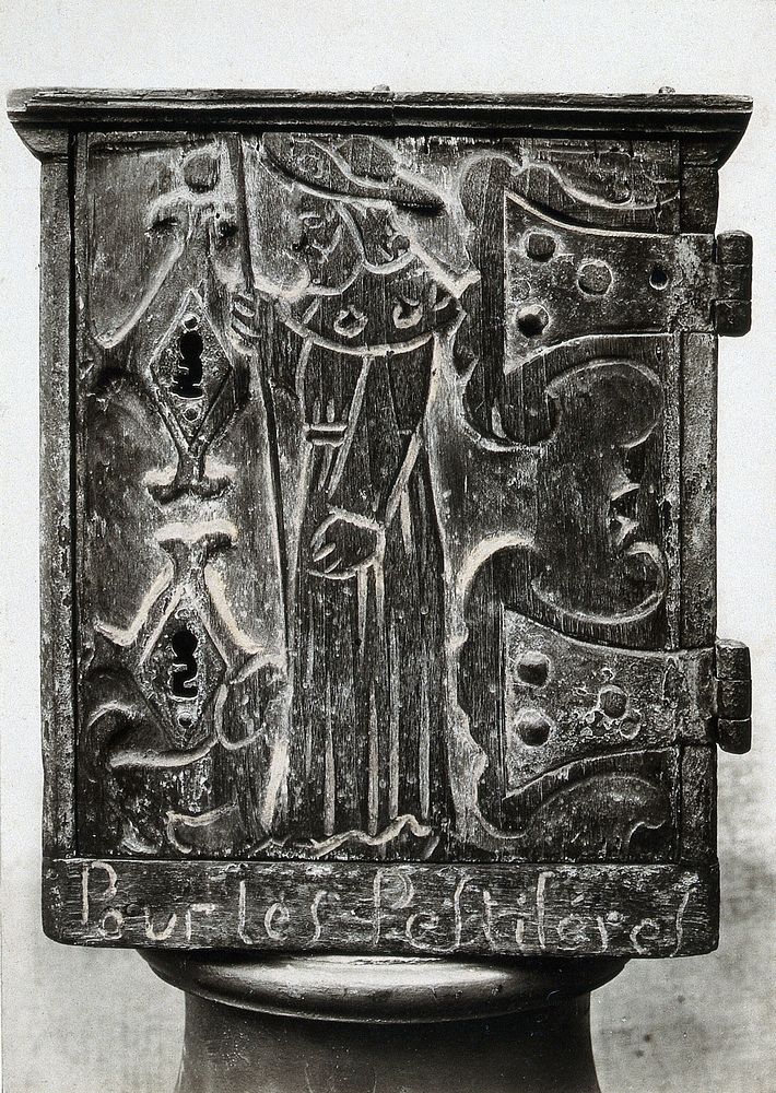 A wooden collection box for the benefit of plague victims, carved in low relief with the figure of Saint Roch as a pilgrim.…