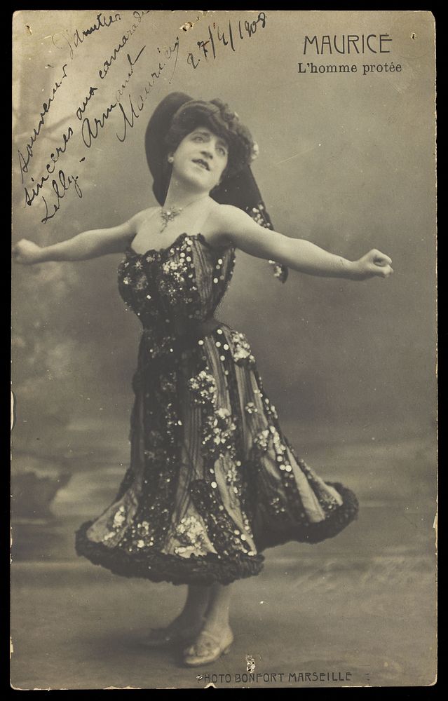 An actor in drag, known as "Maurice"; poses on stage mid-dance. Photographic postcard, 1908.