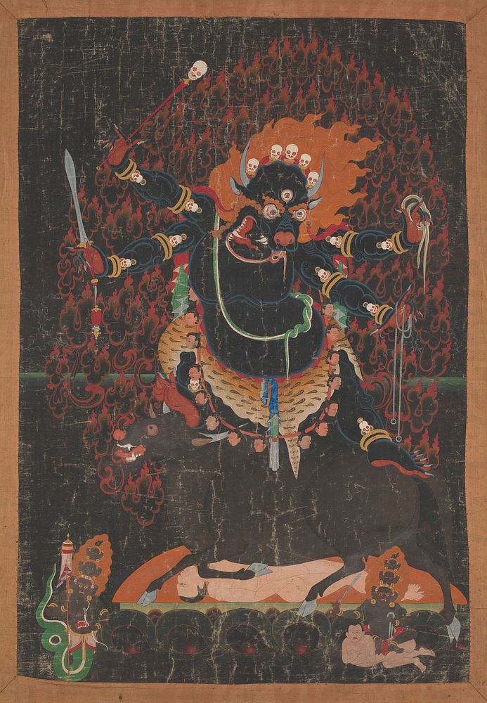 Yama, Buddhist god of death, with the head of a buffalo bedecked with skulls and flames, stands on a bull crushing a man…