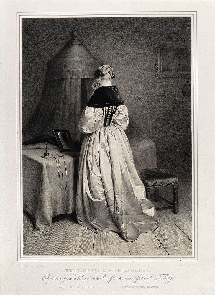 A woman seen from behind standing at her dressing table upon which is placed a powder puff and a mirror; behind is a bed…