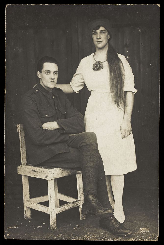 Two prisoners of war, one in drag, pose with a chair. Photographic postcard, 191-.