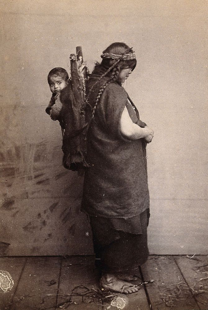 A woman (Native American) carrying a child on her back in a wooden carrier, supported by a strap around her head: studio…