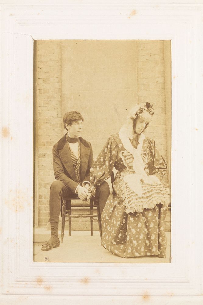 Two men, one in drag, sitting next to each other. Photograph, 189-.