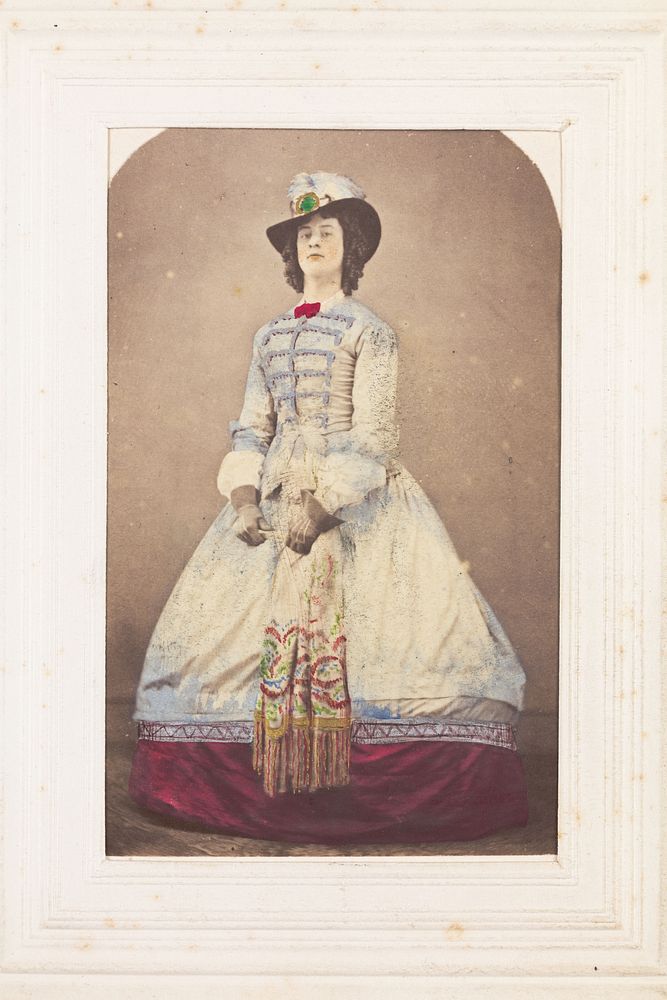 A man in drag wearing an elaborate dress and feathered hat.