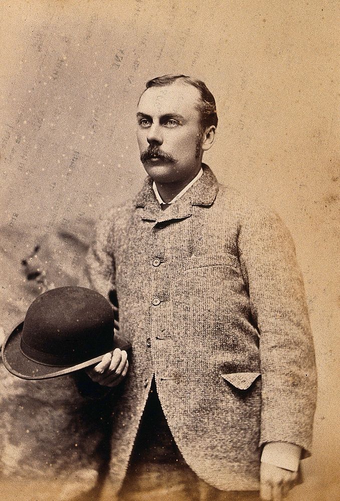 An American man, standing holding a hat: studio portrait. Photograph, ca. 1880.