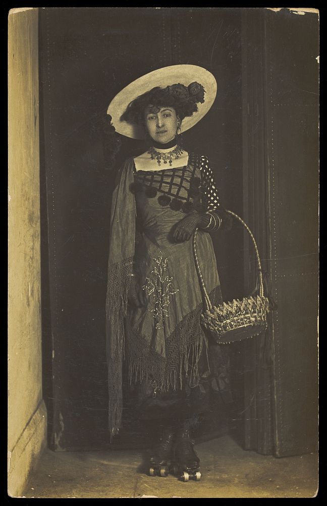 A person wearing a dress, large hat and roller skates, poses holding a basket.