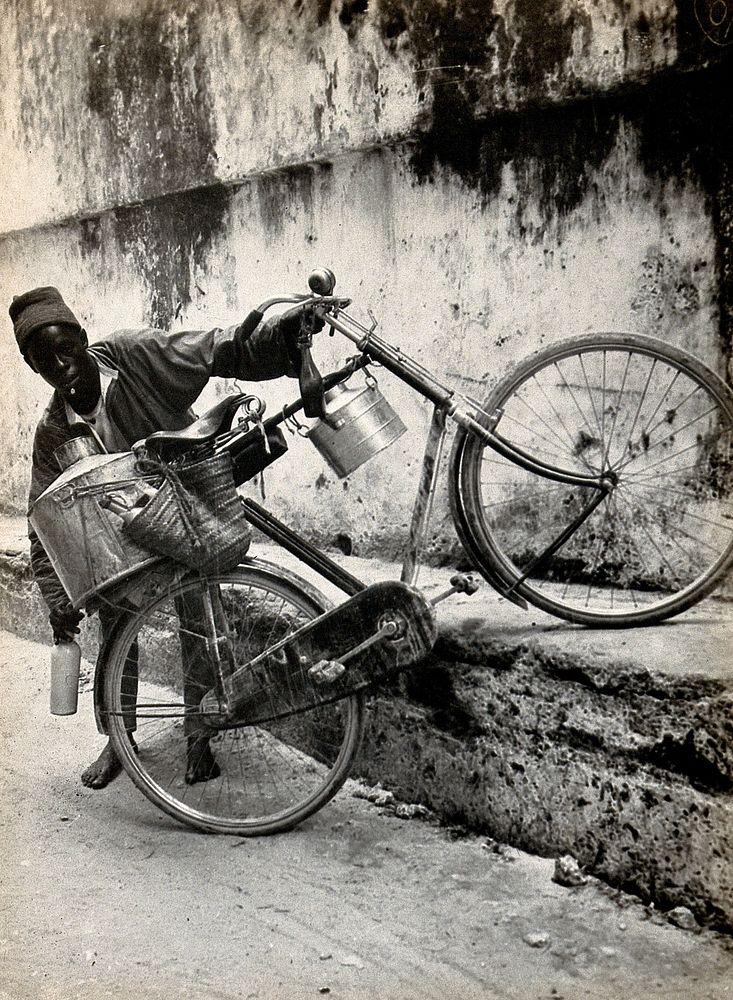 A bicycle with milk pails, held by an African boy, Zanzibar, Tanzania. Photograph by Dr. Andrew Balfour, ca. 1910 .
