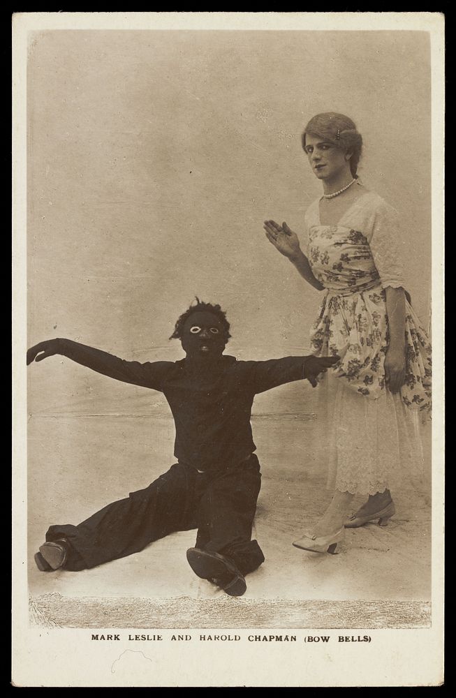 Harold Chapman in drag poses with Mark Leslie dressed as a Golliwog, in an act for the Bow Bells. Photographic postcard, 191…